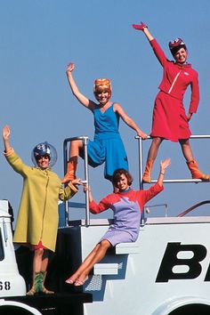 three women are jumping off the back of a truck in front of a blue sky