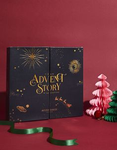 an open book sitting on top of a table next to a christmas tree and ribbon