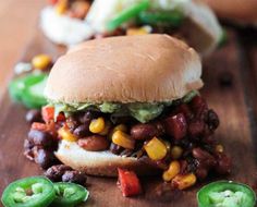 a close up of a sandwich on a cutting board with peppers and jalapenos