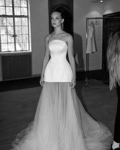 a woman is standing in front of a dress on the floor and she is looking at the camera