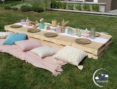 a picnic set up in the grass with plates and cups on it's table