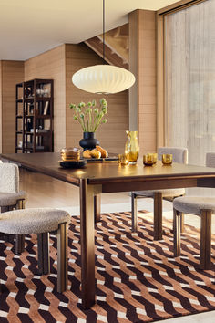 a dining room table and chairs in front of a window with an area rug on the floor