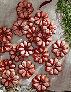 several red and white flowers are on a piece of paper next to some pine branches