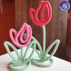 two crocheted flowers sitting on top of a table