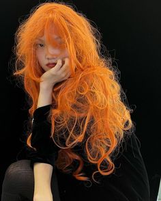 a woman with long orange hair sitting down