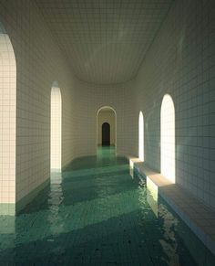 an indoor swimming pool with green tiles and water in the middle, surrounded by arched doorways