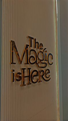 the magic is here written in black on a white background with brown and blue letters