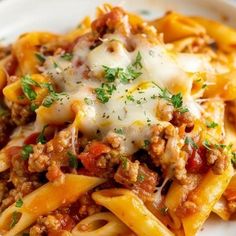 a white plate topped with pasta covered in sauce and cheese