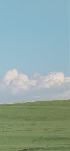 two giraffes standing in the middle of a large open field with clouds