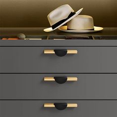 a hat is sitting on top of a filing cabinet with two drawers in front of it