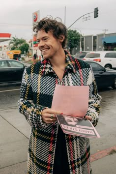 a man standing on the sidewalk holding a pink piece of paper in front of him