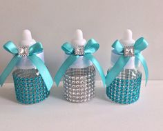 three small bottles decorated with blue and silver sequins, bows and diaper