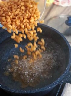 a pan filled with macaroni and cheese being stirred by a ladle over it