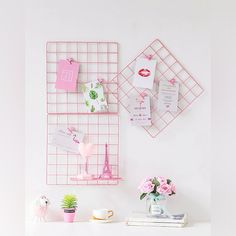 a white desk topped with pink flowers next to a wall mounted memo board on the wall