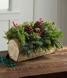 a wooden log filled with pine cones and greenery sitting on top of a table