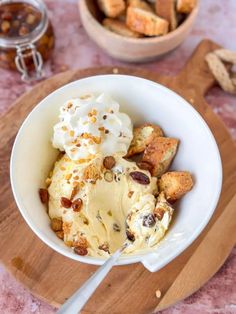 a white bowl filled with ice cream and nuts on top of a wooden cutting board