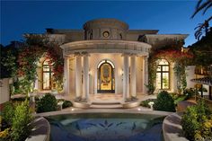 the entrance to a large home with columns and arches on it's sides at night