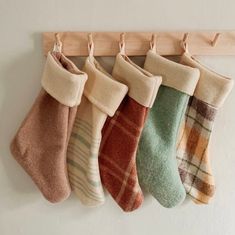 five different colored socks hanging from a wooden hook on a wall next to a white wall