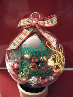 a christmas ornament hanging from the side of a red wall with a bow on it