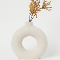 a white vase with some plants in it