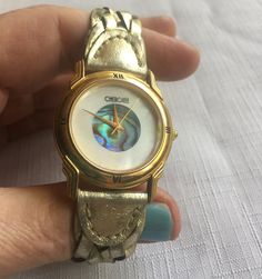 Stylish 80s Cherokee Abalone Watch, has a casual but snazzy beach vibe. Very 80s fashion, but timeless! Comes on its original braided gold tone leather band. Its face measures 1.25" in diameter. Has a new battery so you're all set to go with this one! Please take a look at my storefront at: https://www.etsy.com/shop/FabFinds42?ref=seller-platform-mcnav I have a wide selection of one-of-a-kind items, from clothing and toys to home decor and gift items, and I add new things almost every day! 80s Watch, Unusual Watches, Beach Watch, 1980s Bands, Retro Clock, Retro Watches, Coral Bracelet, Watch Fashion, Fashion Watch