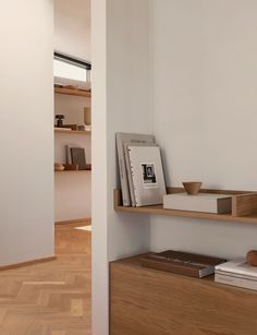 a book shelf with books on top of it in a room that has wood floors and white walls