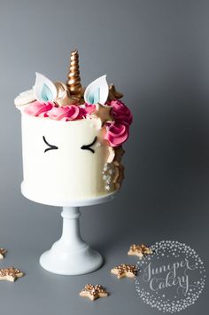 a white cake with pink flowers and a unicorn horn on top