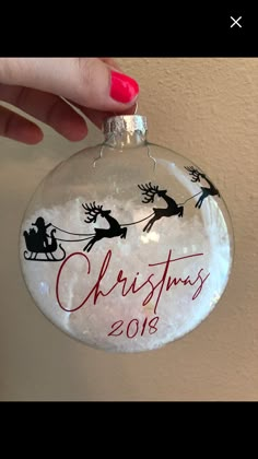 a hand holding a christmas ornament with santa and sleigh on it