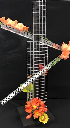 a metal sculpture with flowers in it on a black tableclothed surface and the letter x is decorated with polka dots