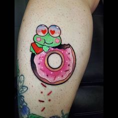 a woman's thigh with a tattoo of a frog on top of a donut