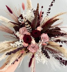 an arrangement of dried flowers and feathers on display