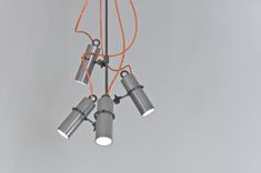 three lights are hanging from the ceiling with orange cords