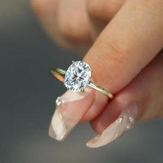 a woman's hand holding an engagement ring with a diamond on the middle finger