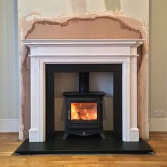 a wood burning stove in a living room with hard wood flooring and white walls