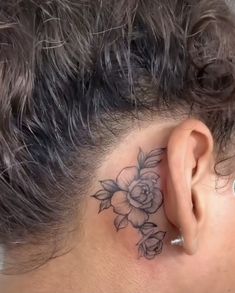 a woman's behind the ear has a small flower tattoo on her left side