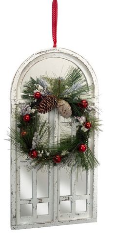 an old window with a wreath and pine cones hanging from the front, on a white background