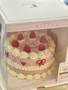 a pink cake with white frosting and strawberries in a box