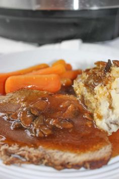 meat, mashed potatoes and carrots on a white plate with gravy