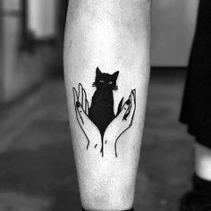 a black and white photo of a cat on someone's leg with two hands holding it