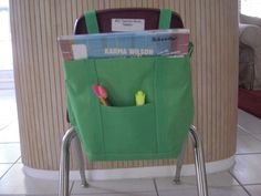 a green shopping cart with books and pens in the pocket, on tiled floor next to wall