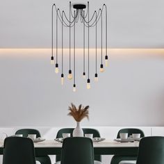 a dining room table with green chairs and a chandelier hanging from the ceiling