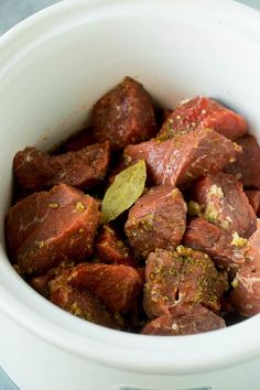 a white bowl filled with meat and seasoning