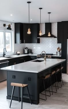 a large kitchen with black cabinets and white counter tops, an island in the middle