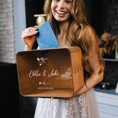 a woman is holding up a wooden box