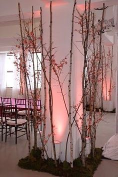 a room with chairs, tables and trees in the center is decorated with pink lights