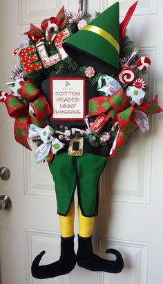 a christmas wreath is hanging on the front door with elf hats and candy canes