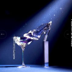 a martini glass being filled with liquid in front of a spotlight on a dark background