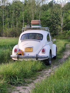 an old vw beetle parked on the side of a dirt road