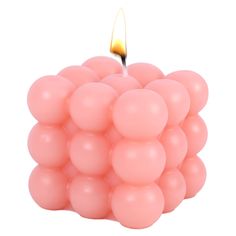 a candle that is sitting in the middle of some pink balls on a white background