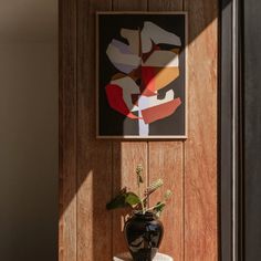 a potted plant sitting on top of a table next to a framed art piece